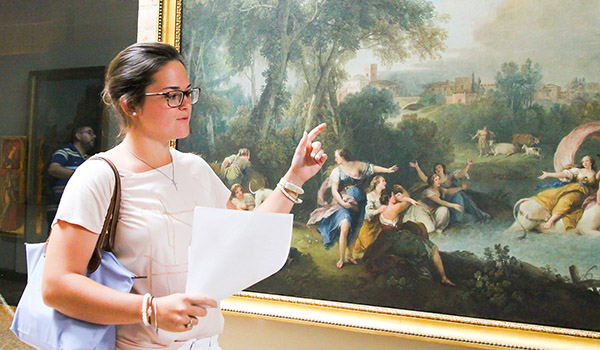 Catholic ϲapp students explaining a painting.